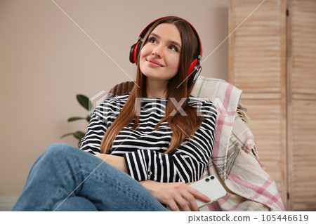 Woman listening to audiobook in chair at home Woman listening to audiobook in chair at home 105446619