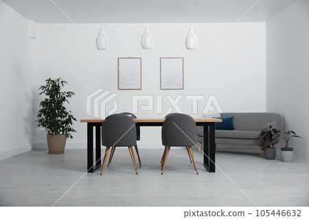 Stylish wooden table and chairs in light room. Modern interior design 105446632