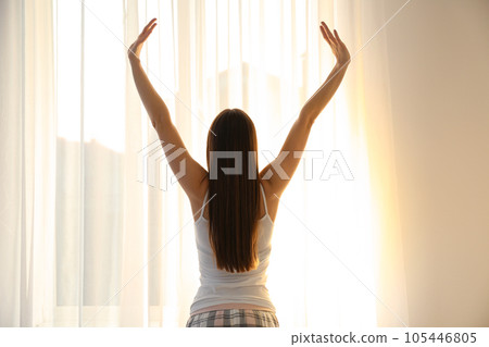 Young woman stretching near window at home. Lazy morning 105446805