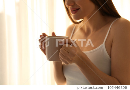 Young woman with cup near window at home, closeup. Lazy morning 105446806