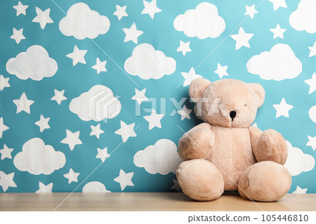 Teddy bear on wooden table near wall with painted blue sky, space for text. Baby room interior 105446810