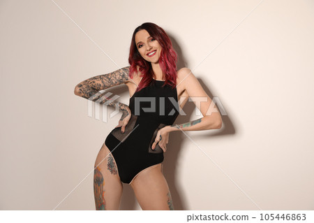 Beautiful woman with tattoos on body against light background 105446863