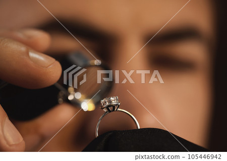 Jeweler working with ring on blurred background, closeup Jeweler working with ring on blurred background, closeup 105446942