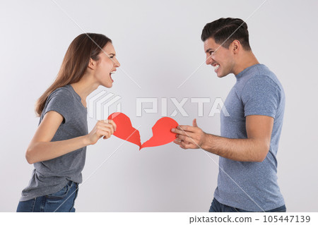 Couple with torn paper heart quarreling on light background. Relationship problems Couple with torn paper heart quarreling on light background. Relationship problems 105447139