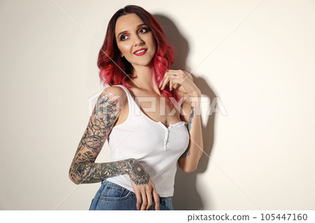 Beautiful woman with tattoos on arms against light background 105447160