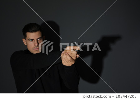Professional killer with gun on black background Professional killer with gun on black background 105447205