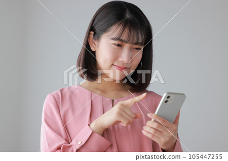 一位穿著休閒服的女士正在操作智能手機_1 一位穿著休閒服的女士正在操作智能手機_1 105447255