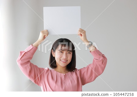 A woman in casual clothes holding a message board above her head_1 A woman in casual clothes holding a message board above her head_1 105447258
