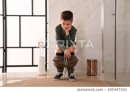 Boy suffering from hemorrhoid on toilet bowl in rest room 105447302