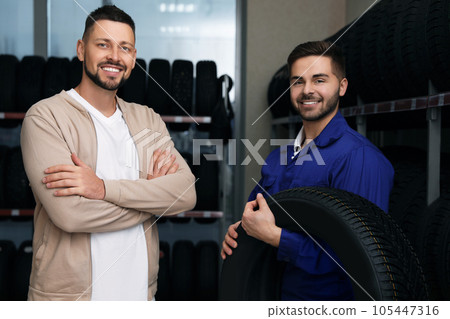Mechanic helping client to choose car tire in auto store 105447316