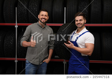Mechanic helping client to choose car tire in auto store Mechanic helping client to choose car tire in auto store 105447318