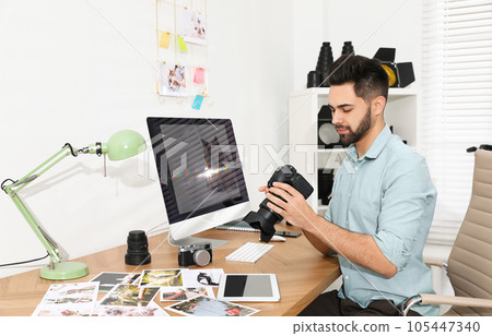 Professional photographer with camera working at table in office 105447340