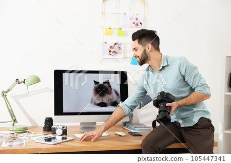 Professional photographer with camera working in light modern office 105447341