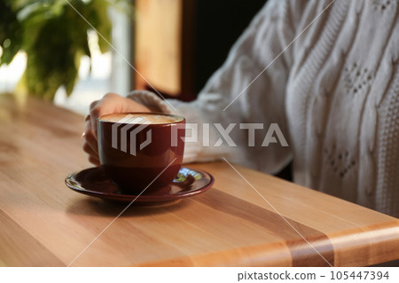 Woman with aromatic coffee at table in cafe, closeup 105447394