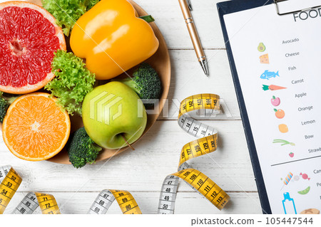 Fruits, vegetables, measuring tape and list of products on white wooden background, flat lay 105447544