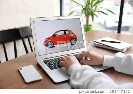 Woman using laptop to buy car at wooden table indoors, closeup Woman using laptop to buy car at wooden table indoors, closeup 105447552