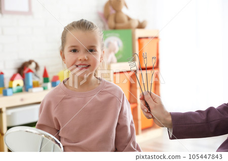 Speech therapist using logopedic probes on session with little girl in office Speech therapist using logopedic probes on session with little girl in office 105447843