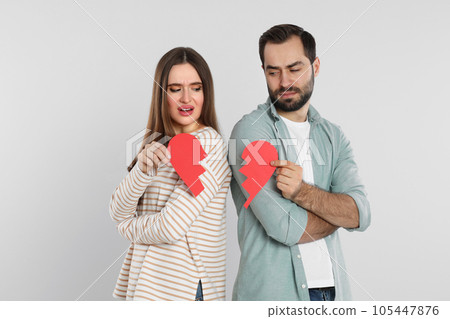 Couple with torn paper heart on light background. Relationship problems 105447876