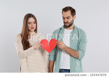 Couple tearing paper heart on light background. Relationship problems Couple tearing paper heart on light background. Relationship problems 105447878