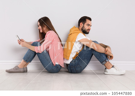 Woman with smartphone ignoring her boyfriend indoors. Relationship problems Woman with smartphone ignoring her boyfriend indoors. Relationship problems 105447880