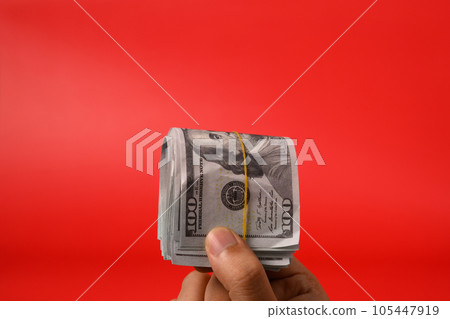 Hand holding hundred dollar bills on red background, Banknotes for money saving, Cash money dollars, Business investment and income, Global financial crisis, Earning and saving money concept Hand holding hundred dollar bills on red background, Banknotes for money saving, Cash money dollars, Business investment and income, Global financial crisis, Earning and saving money concept 105447919