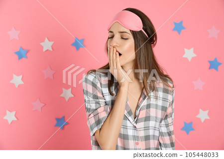Beautiful woman wearing pajamas and sleep mask on pink background. Bedtime 105448033