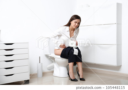 Woman with stomach ache sitting on toilet bowl in bathroom 105448115