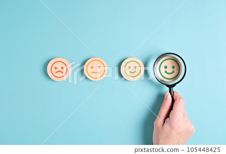 satisfaction with smiley face emoticon on wooden yellow background. 105448425