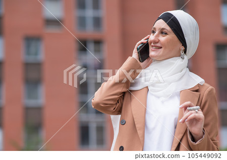 Young woman in hijab talking on smartphone outdoors.  105449092