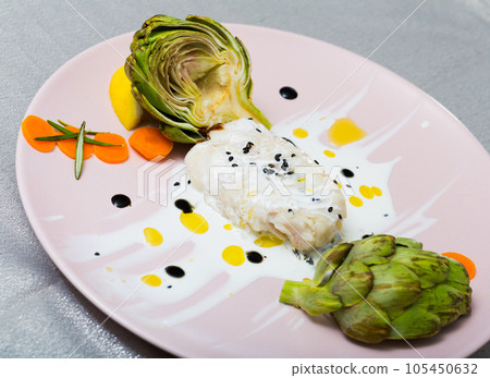 Tasty fried hake fillet with sauce and artichokes on plate 105450632