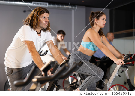 Sporty man working out on stationary bicycle in gym 105450712