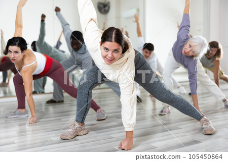Cheerful young lady learning new modern dance in group dance lesson 105450864