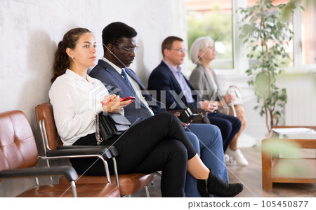 Young female visitor sitting on the bench in waiting room of clinic Young female visitor sitting on the bench in waiting room of clinic 105450877