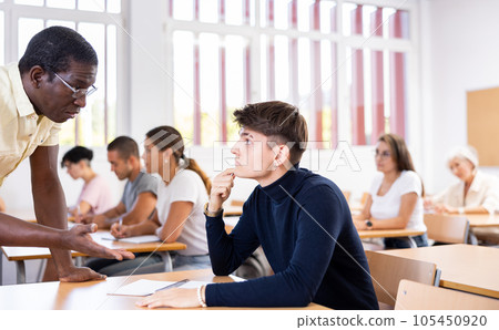 Young man listening to teacher during classes in university Young man listening to teacher during classes in university 105450920