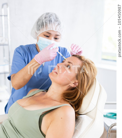 Asian doctor doing anti-aging beauty procedures to elderly patient t 105450987