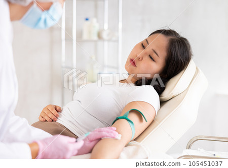 Middle-aged doctor giving injection into vein Middle-aged doctor giving injection into vein 105451037