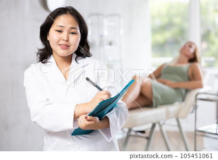Asian professional cosmetologist advertising facial procedure to patients 105451061