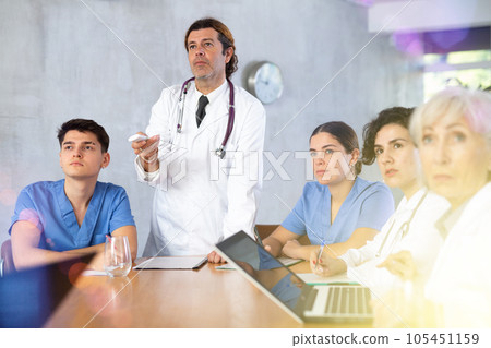 Doctor switching slides of presentation during medical consultation with colleagues 105451159
