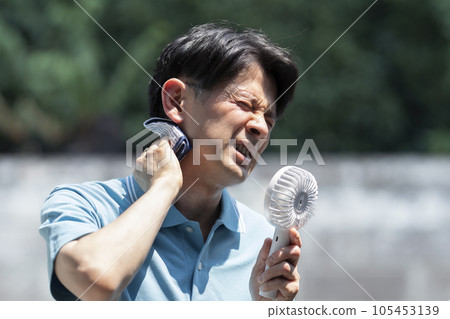 Image of intense heat Man wiping sweat Handy fan 105453139