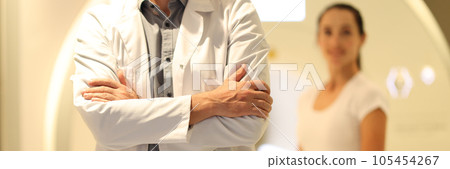 Close-up of doctor standing close-up and blurred patient and CT scanner in background. 105454267