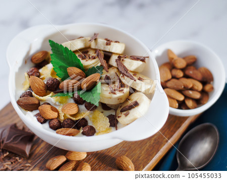 Almond banana salad with chocolate and milk in white plate. Healthy nutritious breakfast. Top view 105455033