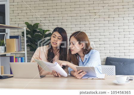 Happy success business woman partner working together in company office corporate executive teamwork. Meeting Executive Asian business woman using laptop office desk with fist arm raised win happiness 105456365