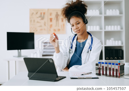 Attractive African female doctor talking while explaining medical treatment to patient through a video call with laptop in office or laboratory Attractive African female doctor talking while explaining medical treatment to patient through a video call with laptop in office or laboratory 105457507