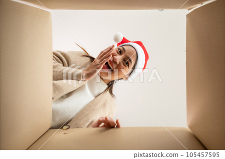 Happy young asian woman wearing christmas hat and unpacking gift box 105457595