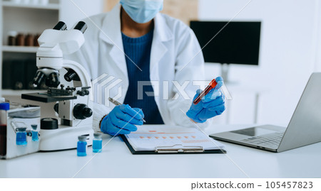 Modern medical research laboratory. African female scientist working with micro pipettes analyzing biochemical samples, advanced science chemical laboratory for medicine. . Modern medical research laboratory. African female scientist working with micro pipettes analyzing biochemical samples, advanced science chemical laboratory for medicine. . 105457823