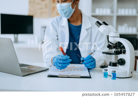 Modern medical research laboratory. African female scientist working with micro pipettes analyzing biochemical samples, advanced science chemical laboratory for medicine. . 105457827