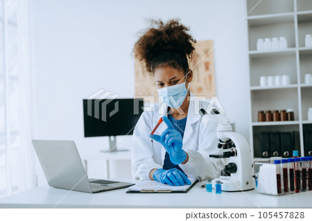 Modern medical research laboratory. African female scientist working with micro pipettes analyzing biochemical samples, advanced science chemical laboratory for medicine. . Modern medical research laboratory. African female scientist working with micro pipettes analyzing biochemical samples, advanced science chemical laboratory for medicine. . 105457828