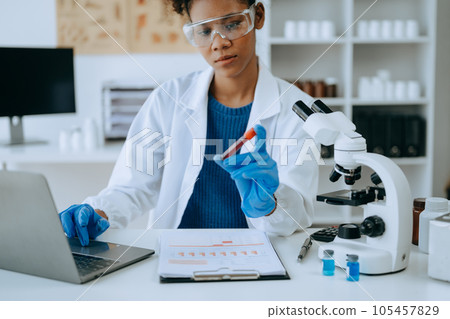 Modern medical research laboratory. African female scientist working with micro pipettes analyzing biochemical samples, advanced science chemical laboratory for medicine. . 105457829