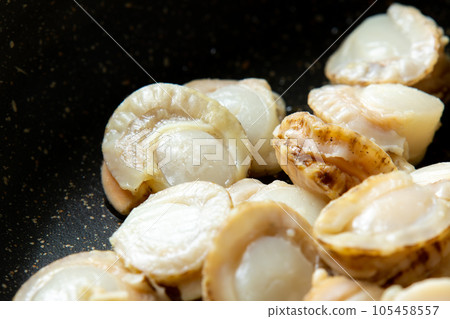 A cooking scene where scallops are fried in a frying pan. A cooking scene where scallops are fried in a frying pan. 105458557