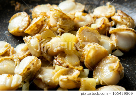 A cooking scene where scallops (boiled scallops) and garlic are fried in a frying pan. A cooking scene where scallops (boiled scallops) and garlic are fried in a frying pan. 105459809